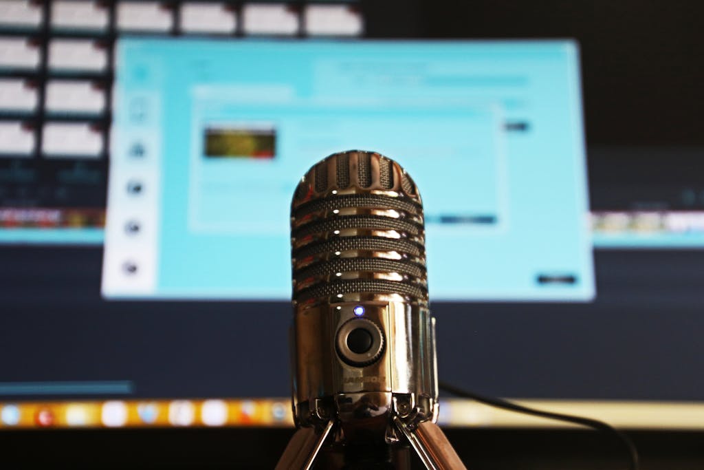 Close-up of a microphone with a computer screen in the background.