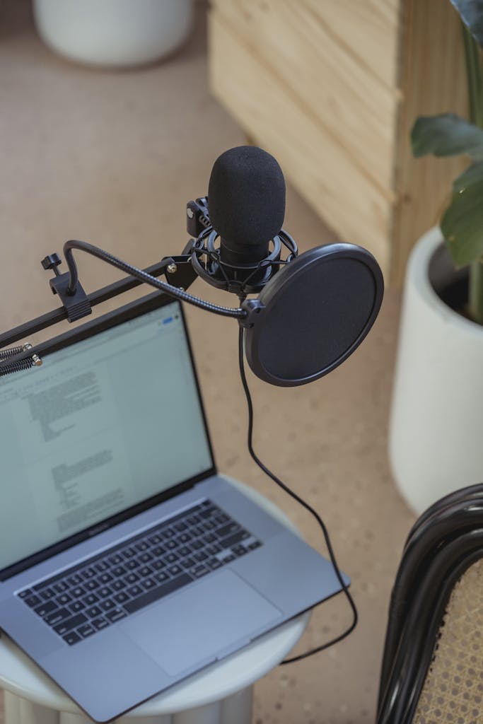 A modern setup featuring a laptop and studio microphone on a desk.