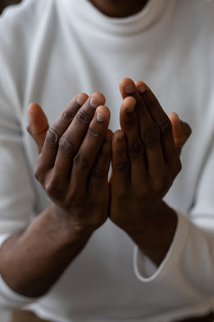 African American man wearing white turtleneck praying with open hands